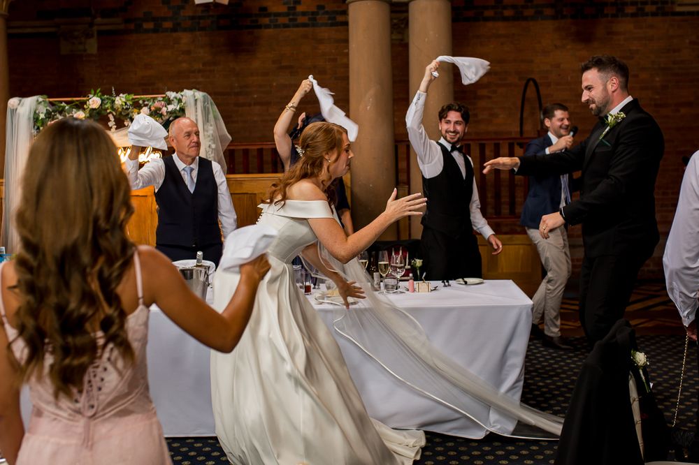 Joyful wedding guests participate in napkin waving tradition during reception festivities.