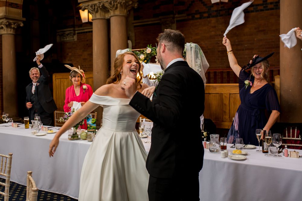 Reception guests participate in traditional napkin wave celebration at elegant wedding venue.