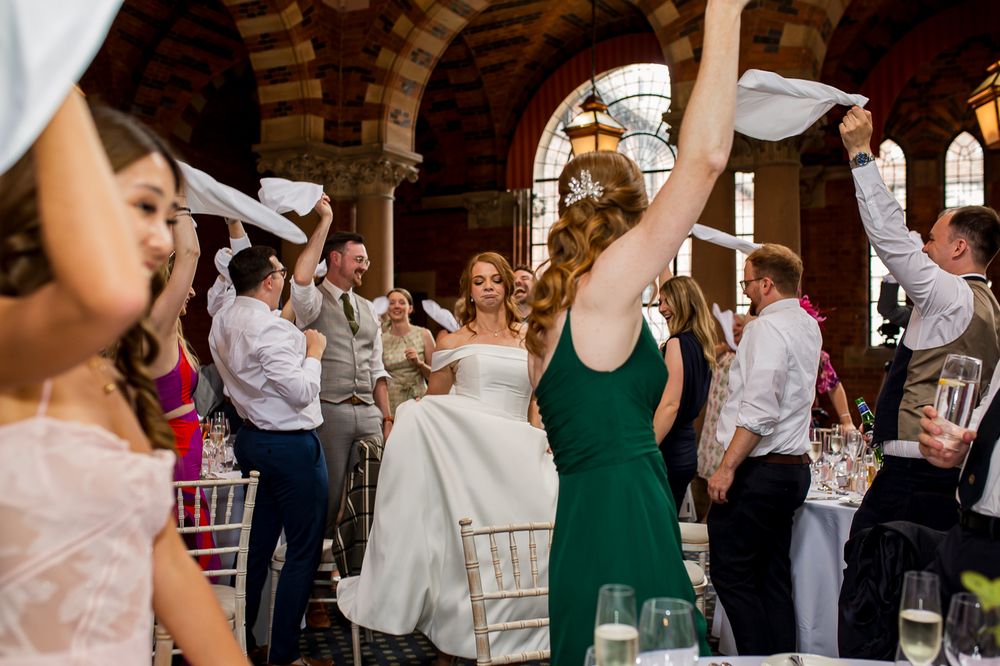 Wedding guests wave white napkins in celebration during reception festivities.