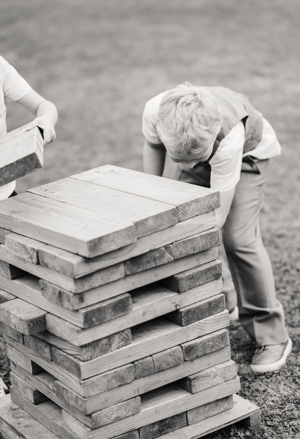 Black and white photo of Jenga into a neat stack on the ground. Waterside Country Barn and Mill lakeside. Relaxed Somerset Wedding photos