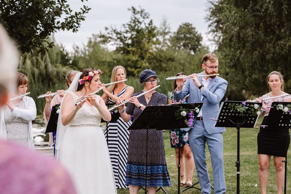 Flautists perform outdoors  during a summer wedding at the Waterside Country Barn and Mill lakeside wedding venue near Taunton, Somerset .