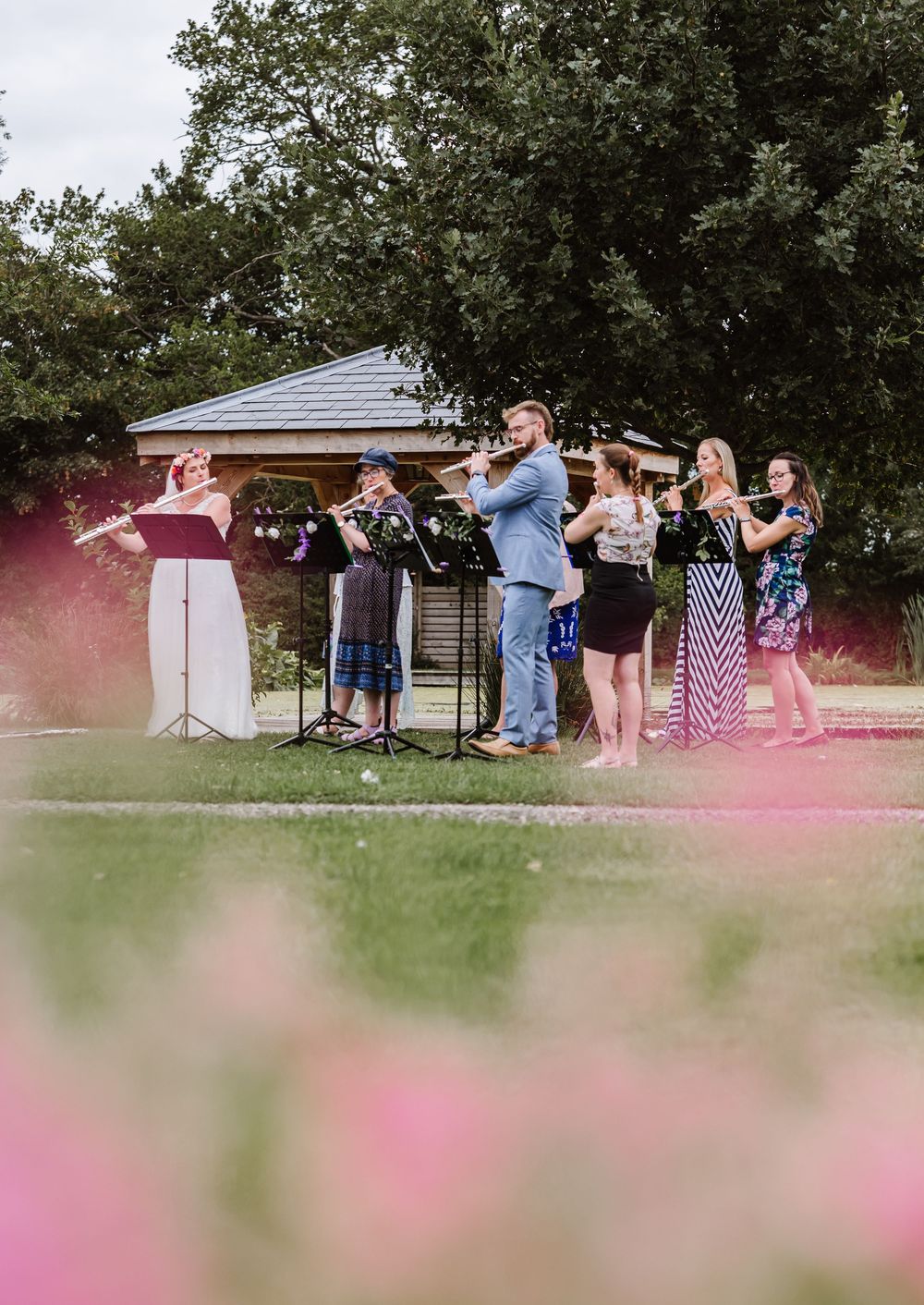 Flautists perform outdoors  during a summer wedding at the Waterside Country Barn and Mill wedding lakeside venue near Taunton, Somerset .