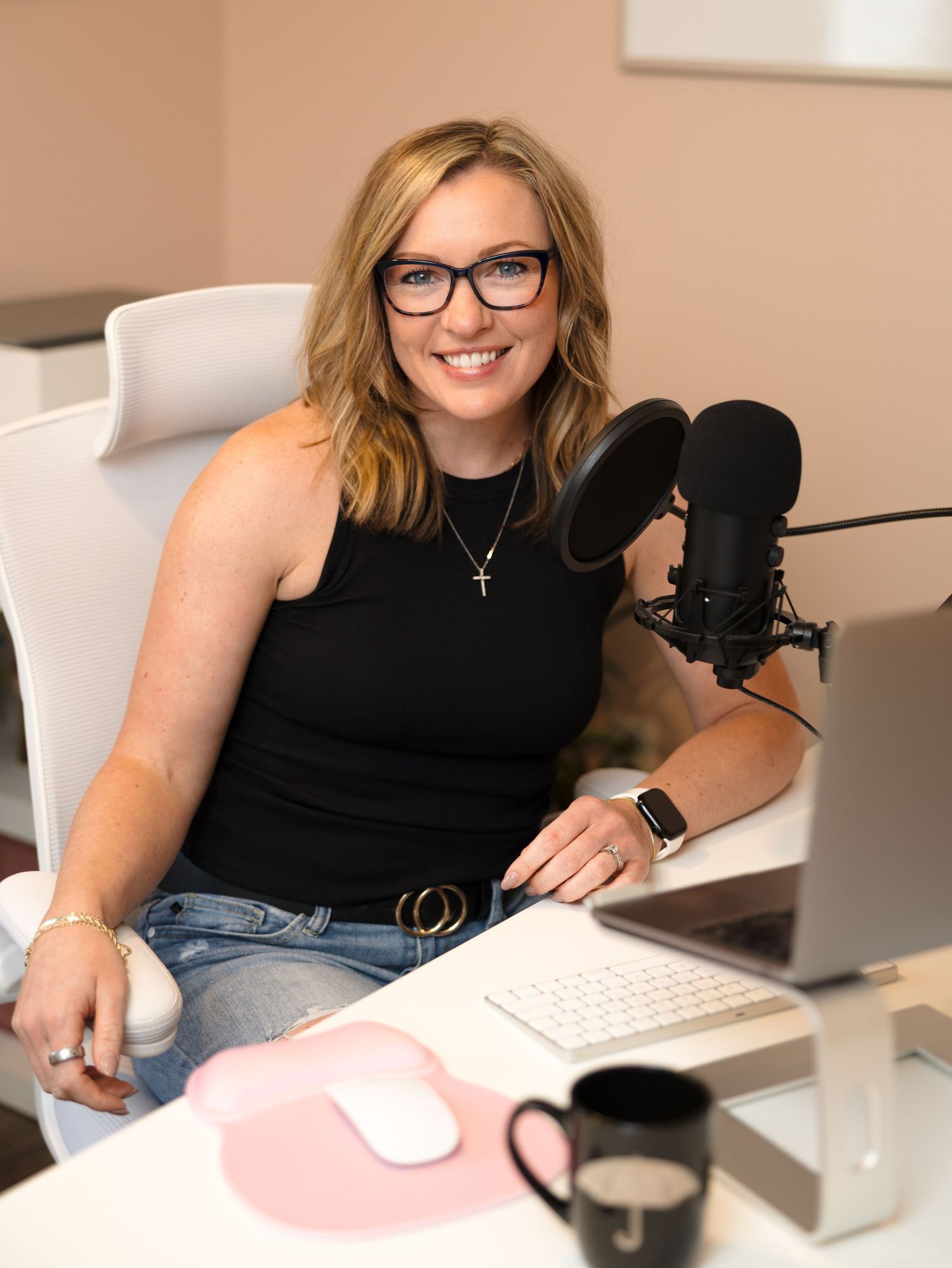 Professional content creator working at desk with microphone, keyboard and computer setup in home office environment.