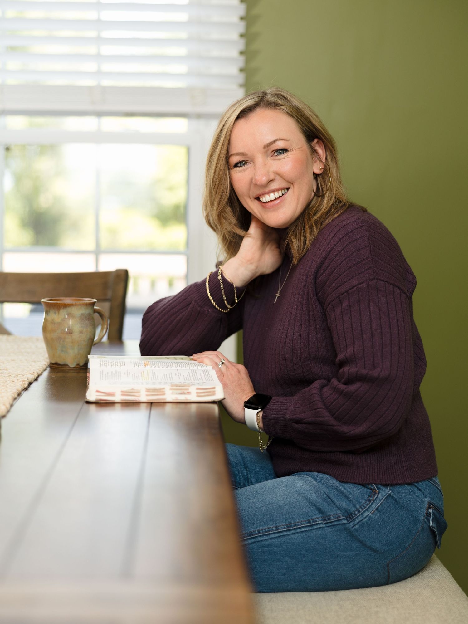 Lifestyle portrait against green wall showing relaxed pose on kitchen counter.