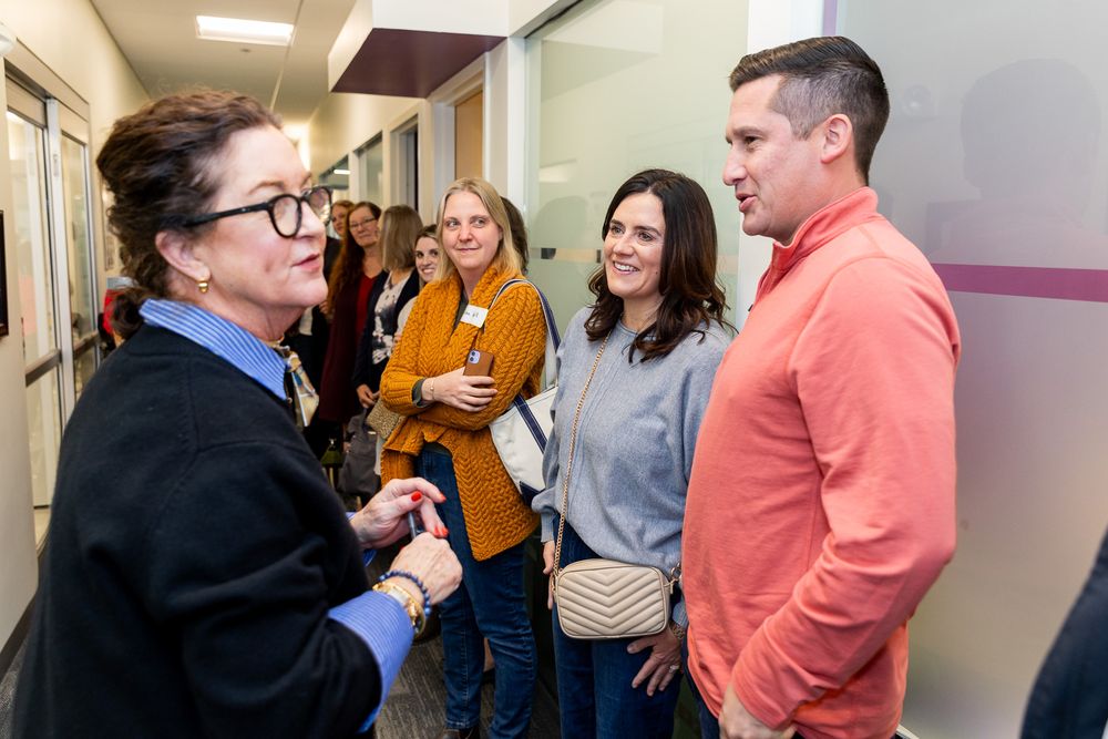 People gathered in a hallway having conversations in a professional or academic setting.