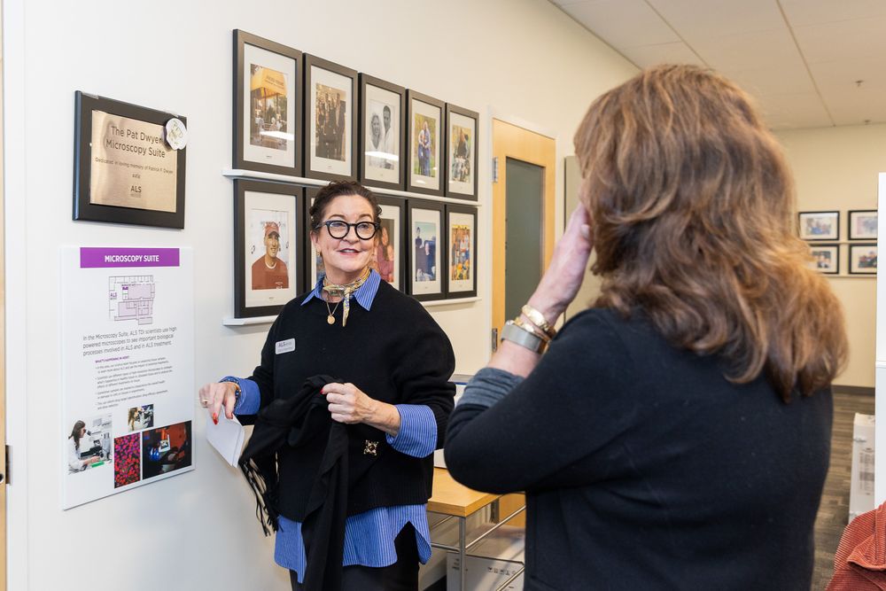 People viewing framed photographs displayed on a wall in an art gallery or exhibition space.