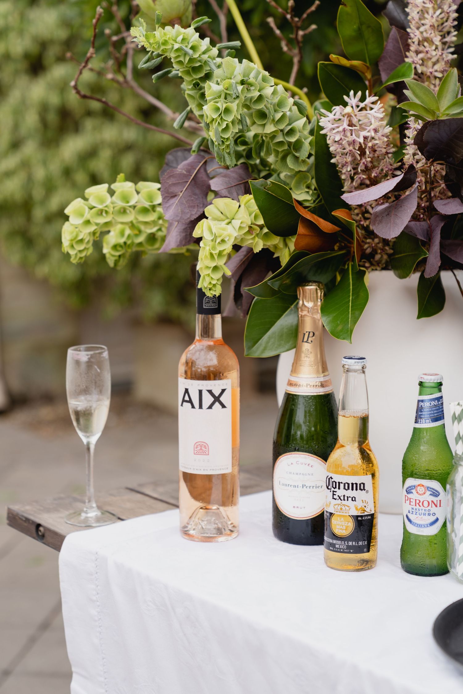 Assorted drinks including AIX rose, champagne, and Corona bottles on a white tablecloth.