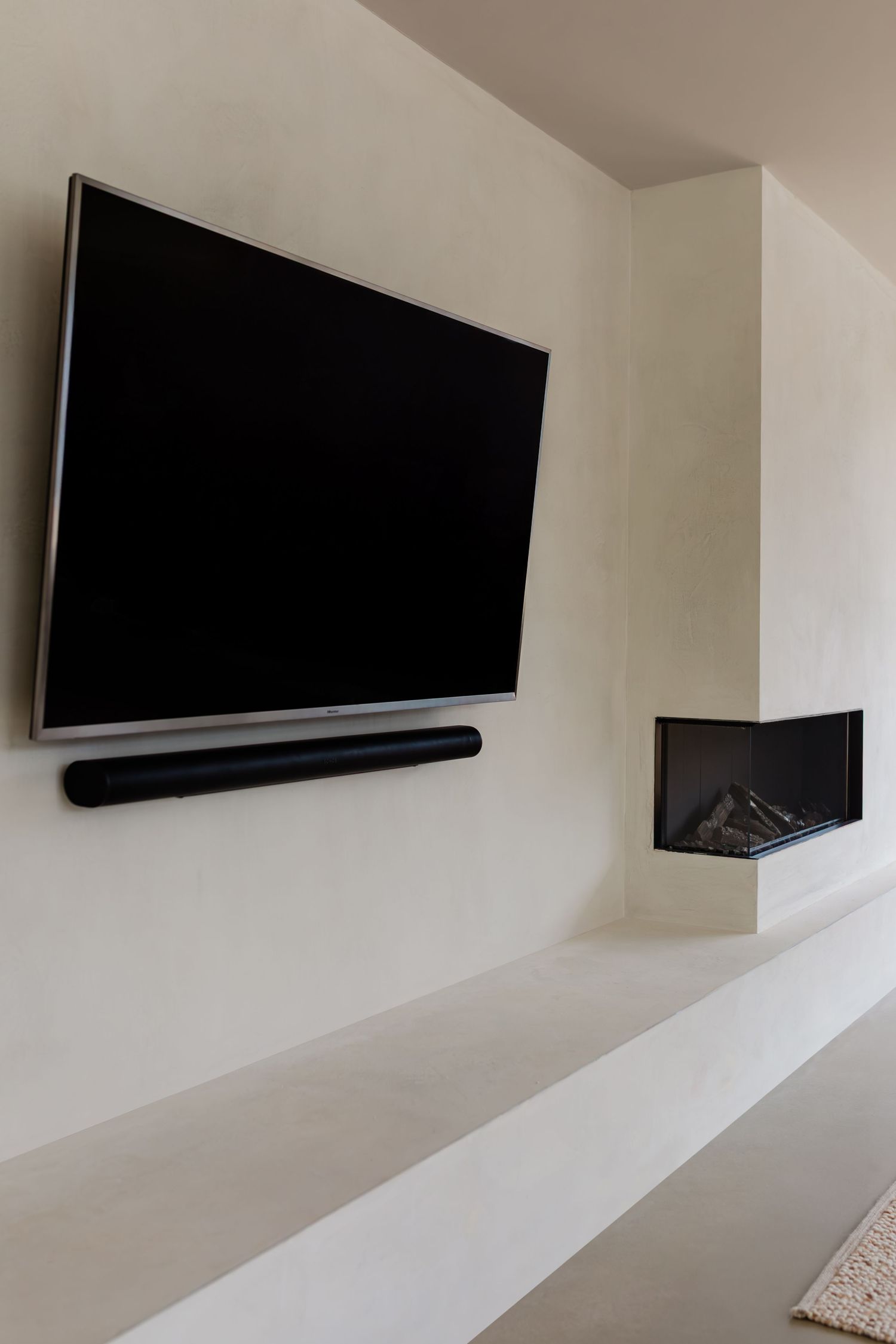 Multiple flat screen televisions mounted on a white wall with a soundbar visible beneath one of the screens.