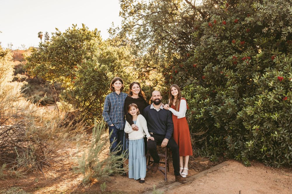 Group stands together on nature trail surrounded by lush greenery during sunset.