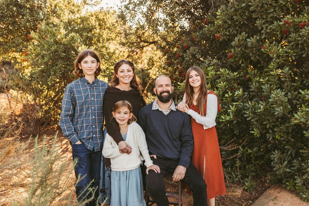 Family group poses together outdoors during golden hour autumn photoshoot in natural setting.