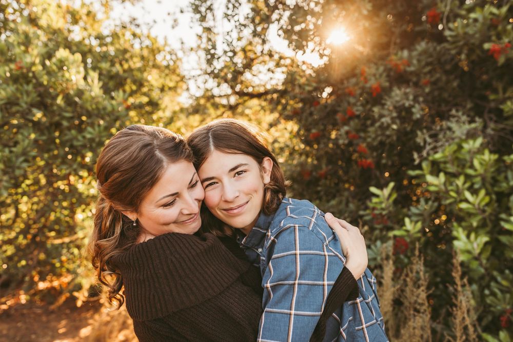Warm sunset light filters through autumn trees creating a cozy golden glow during an outdoor photo session.