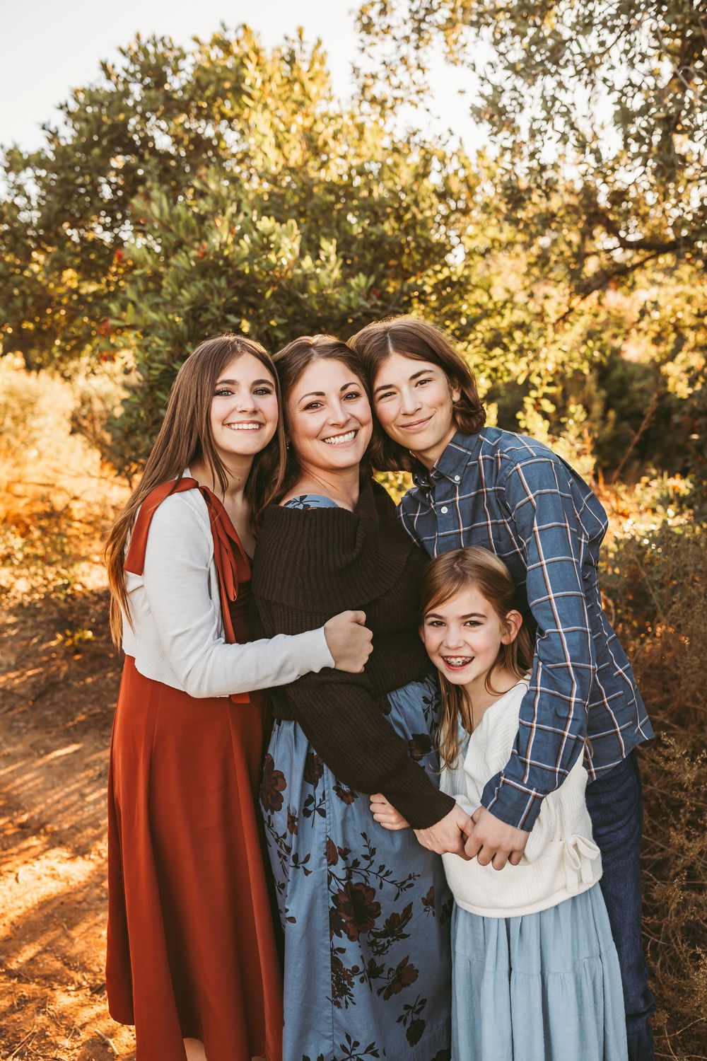A group poses together for casual outdoor family photos with warm autumn lighting.
