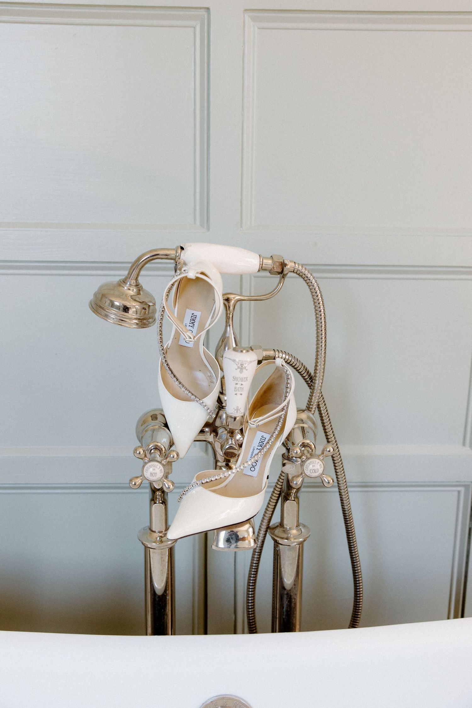 Stylish white wedding shoes with crystal embellishments displayed against a light background.