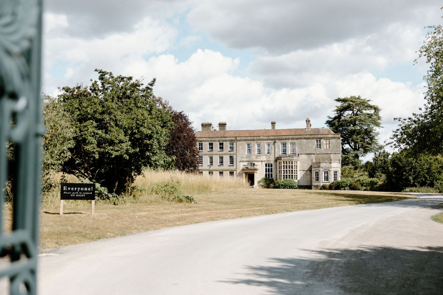Panoramic view of a stately wedding venue with cloudy sky and manicured grounds.