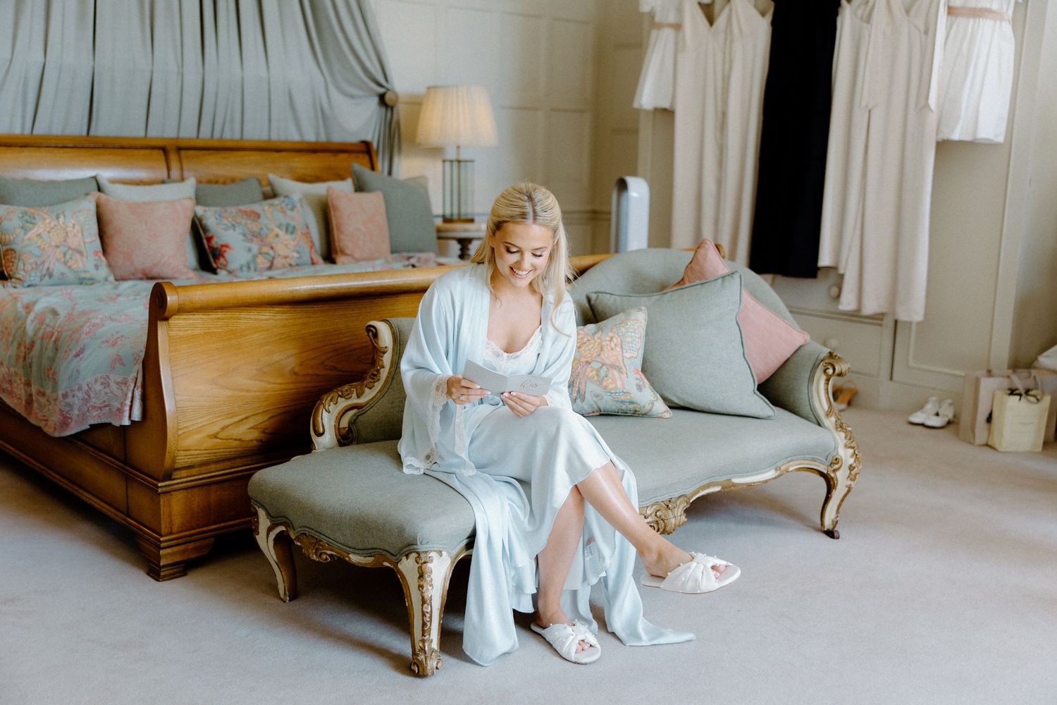 Bride in elegant white dress sitting on vintage furniture in luxurious room.
