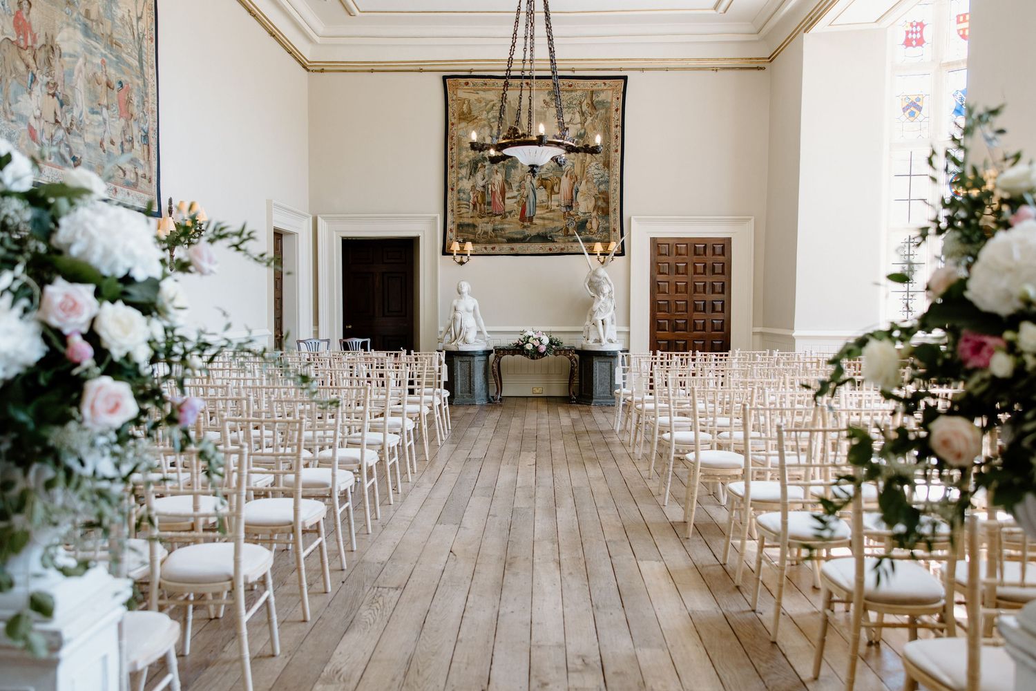 Elegant white wedding ceremony space with white chairs and floral arrangements.