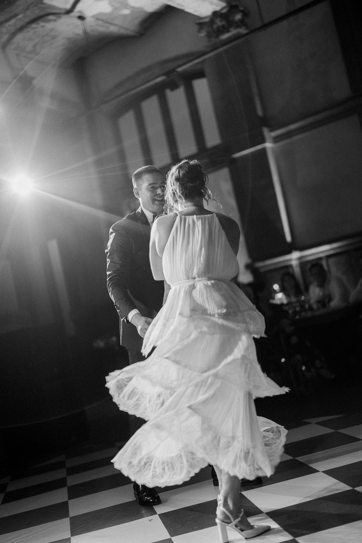 Dancers twirl gracefully on a black and white checkered dance floor during an elegant ballroom event.