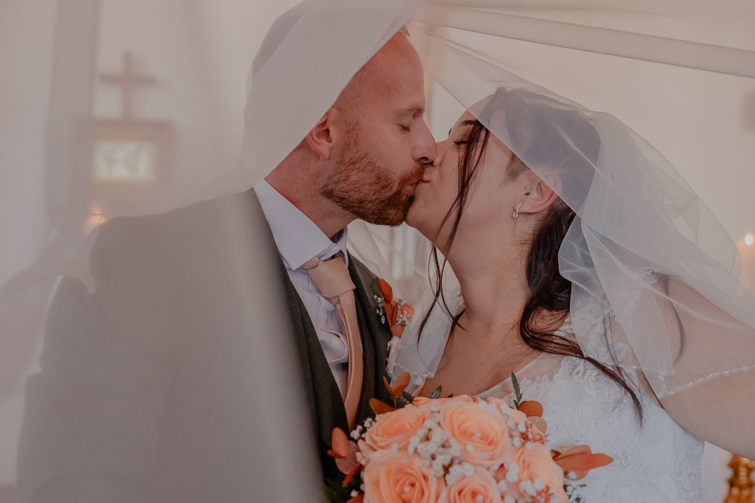 A romantic wedding kiss captured in soft lighting during an intimate ceremony.