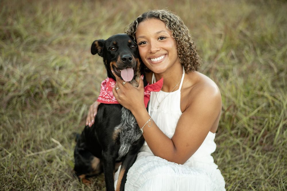 A collection of outdoor wedding photos showing a bride in a white dress posing with a black dog in a grassy field.