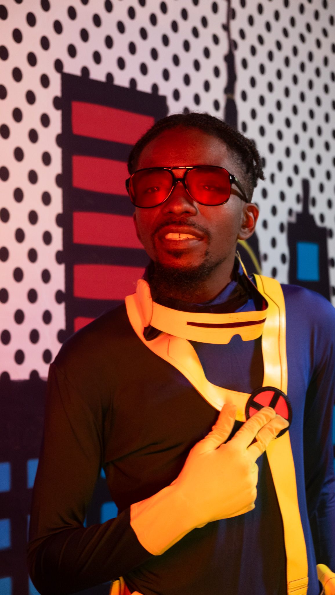 A sequence of four photos showing someone in red sunglasses and a dark shirt making expressive poses against a polka dot background.