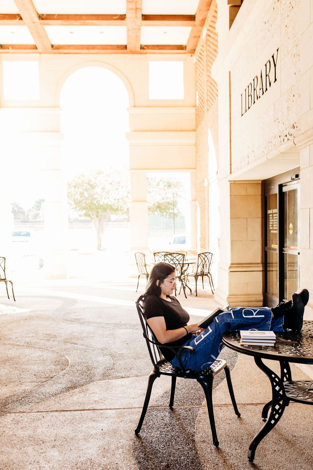 A person sits alone in a covered outdoor hallway reading on a bench in a series of progressive shots.