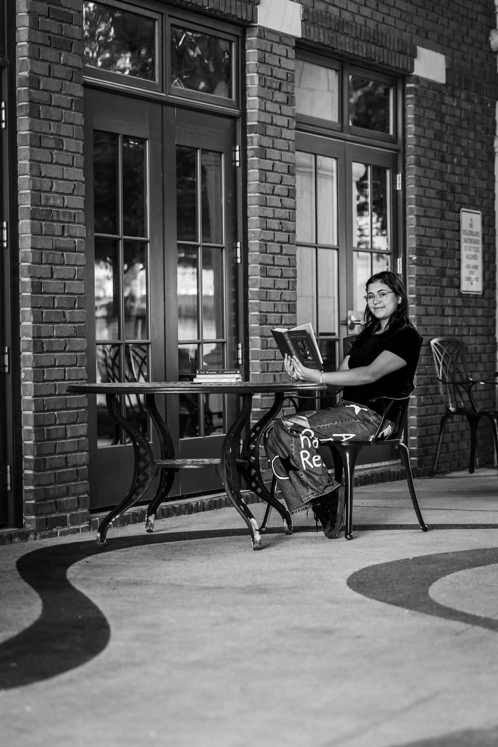 Black and white photo series showing a person sitting on a bench outside a brick building with large windows.