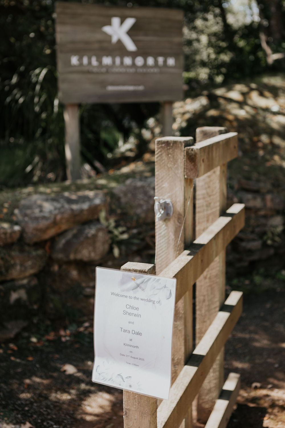 Welcome wedding sign at Kilminorth venue entrance with wooden fence and lush greenery.
