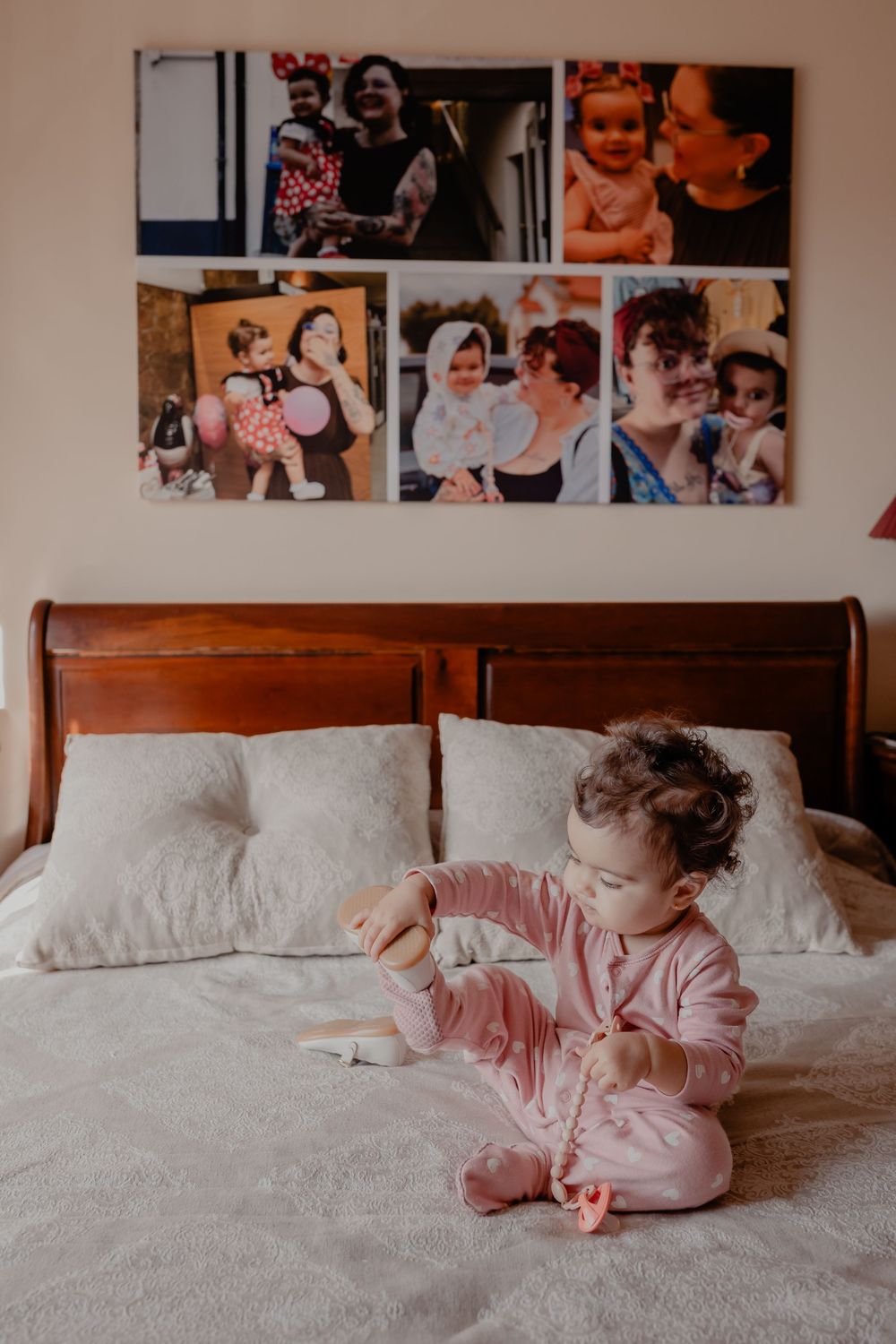 Family photos hang above a comfortable bed with white linens in a peaceful bedroom setting.