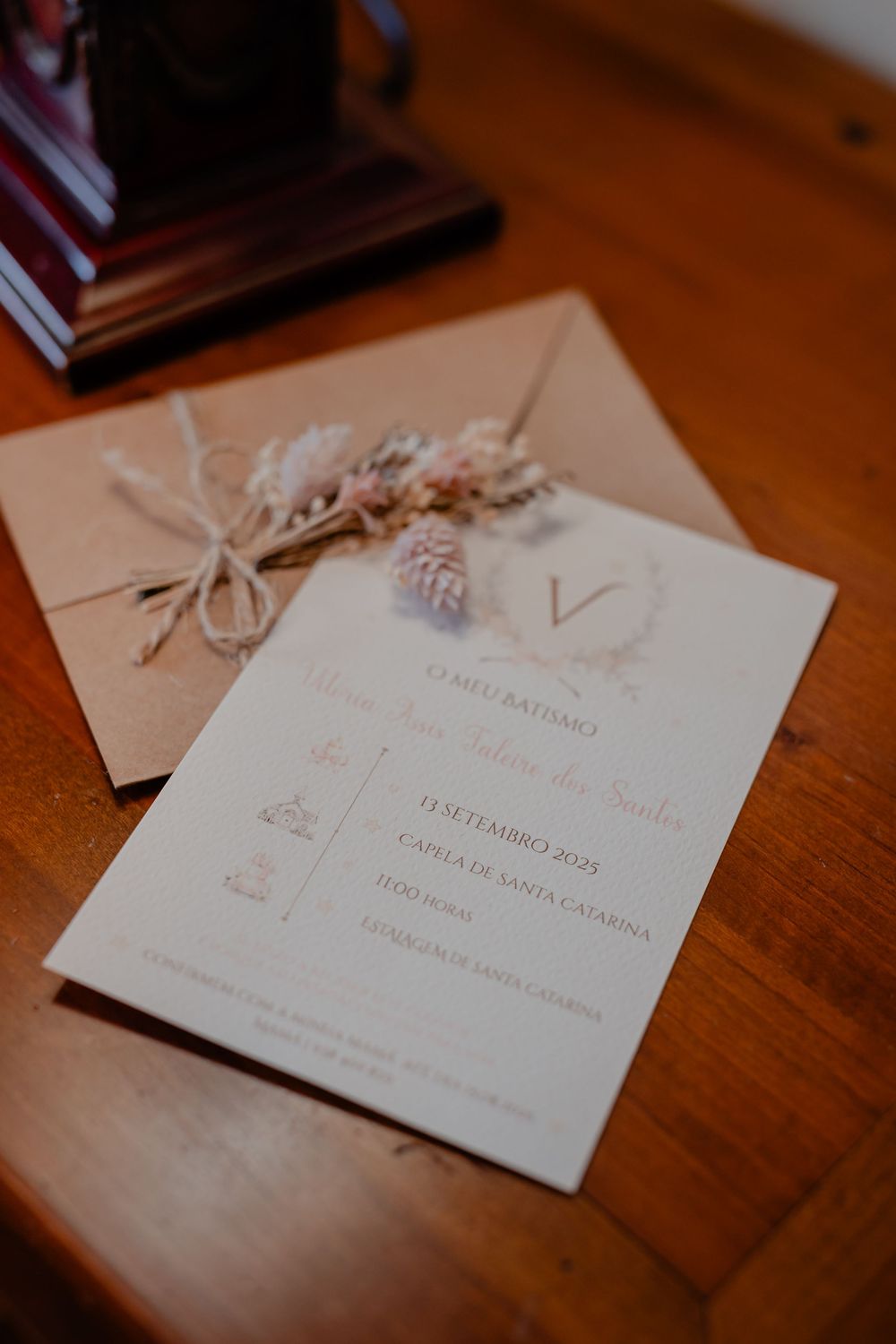 An elegant wedding invitation with dried flowers and twine on a wooden surface.