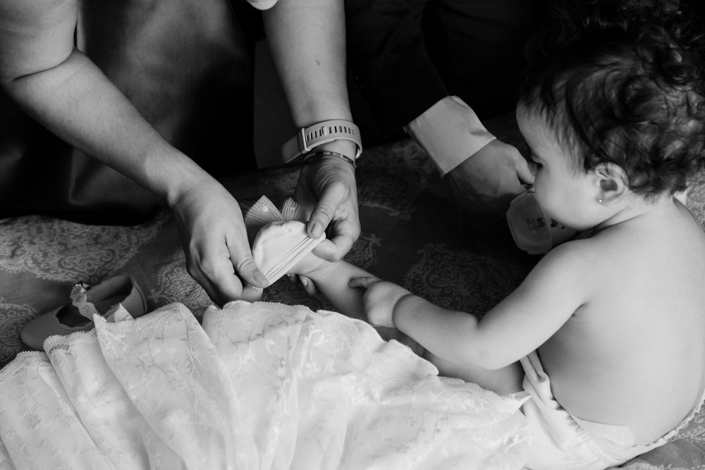 Black and white close-up shot of hands adjusting clothing details during a photo session.