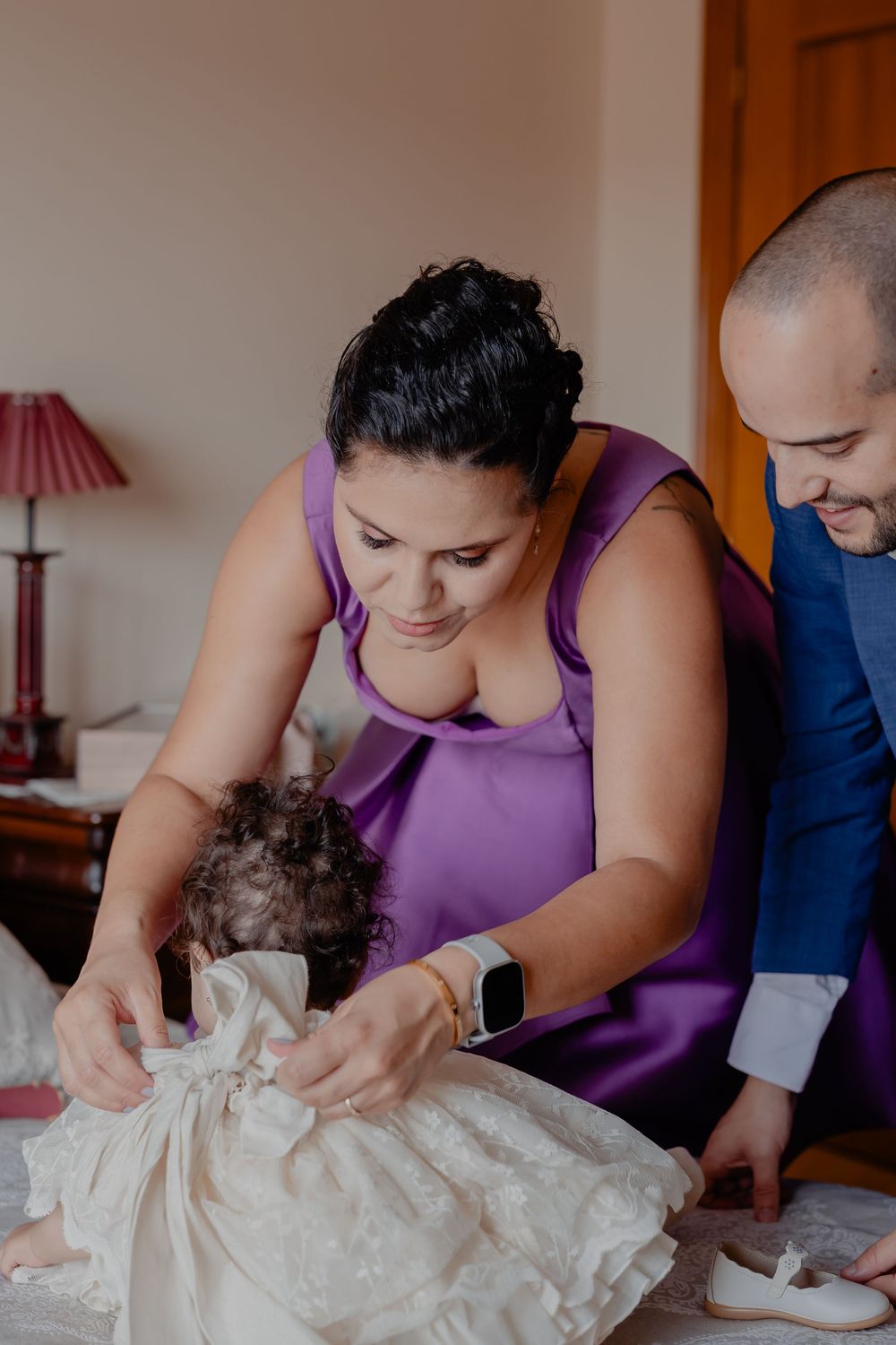 People in purple and blue attire prepare clothing details in an indoor setting.