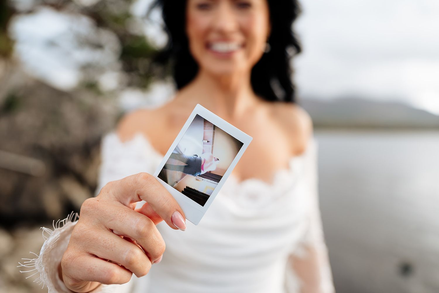 A collection of instant polaroid photographs being held up in front of a blurred outdoor background.