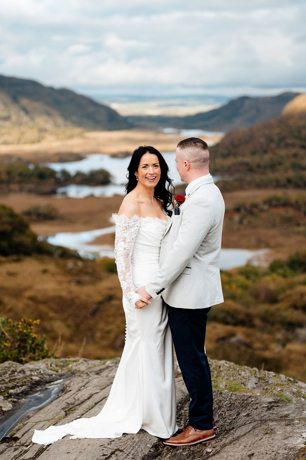 Wedding couple shares intimate moments against a stunning mountain landscape with a winding river below.