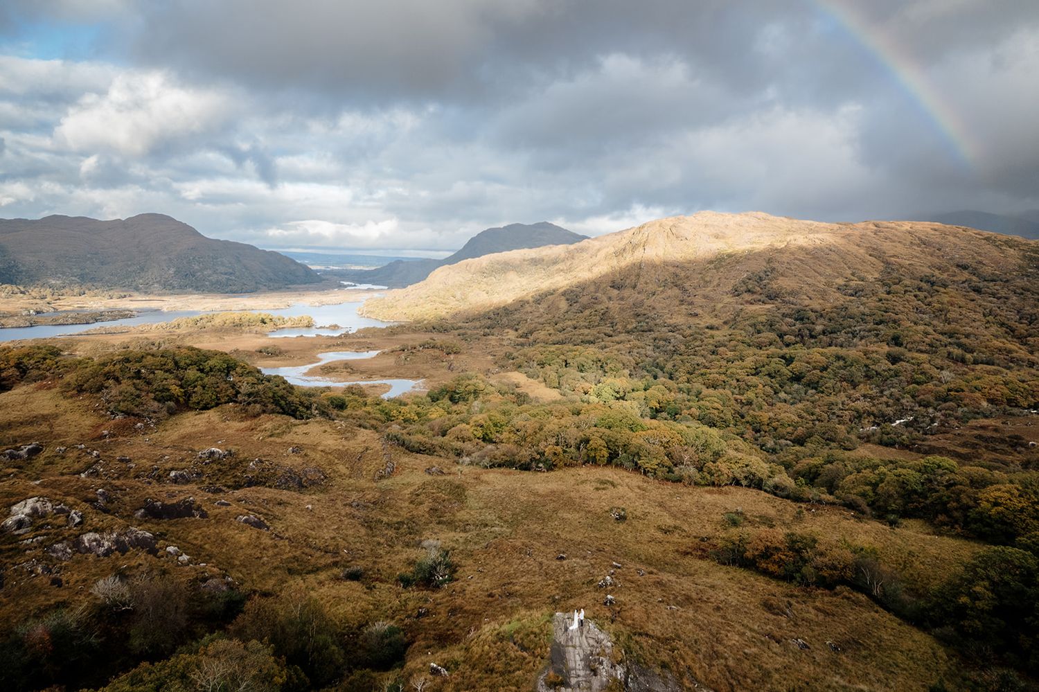 Panoramic view of rugged mountain landscapes in Scotland with dramatic cloudy skies and winding roads.