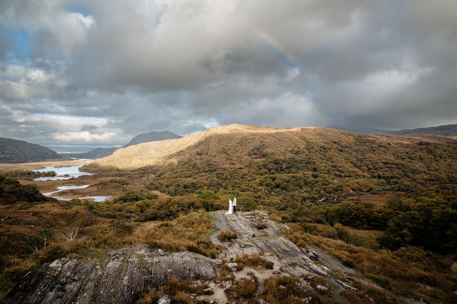 Dramatic landscape of Ireland's rugged coastline with rolling hills and moody clouds over the Atlantic Ocean.