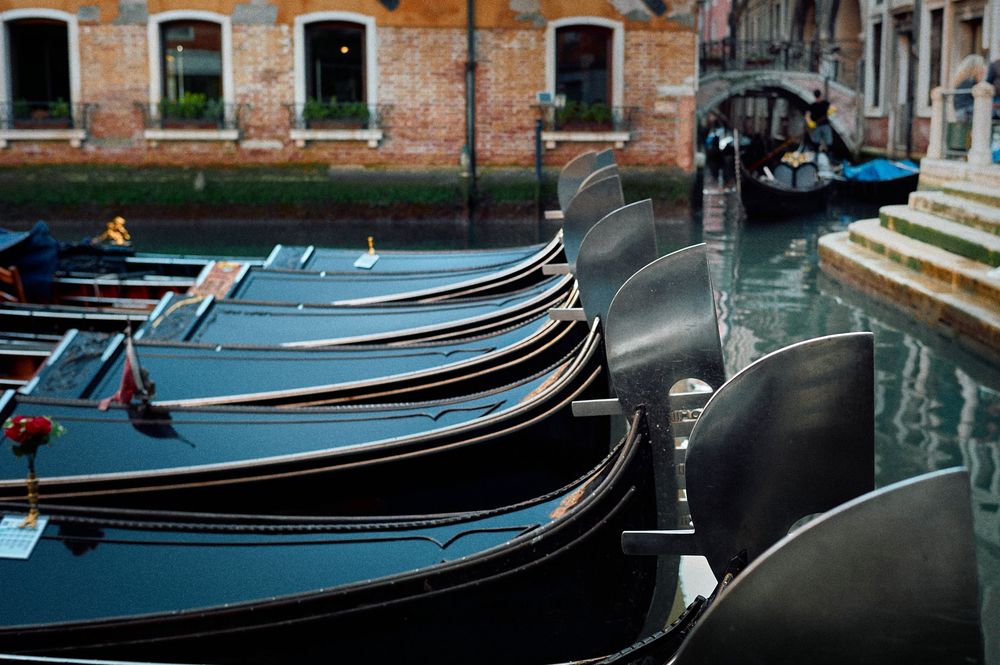Traditional wooden gondolas lined up along a Venetian canal with historic brick buildings in the background.