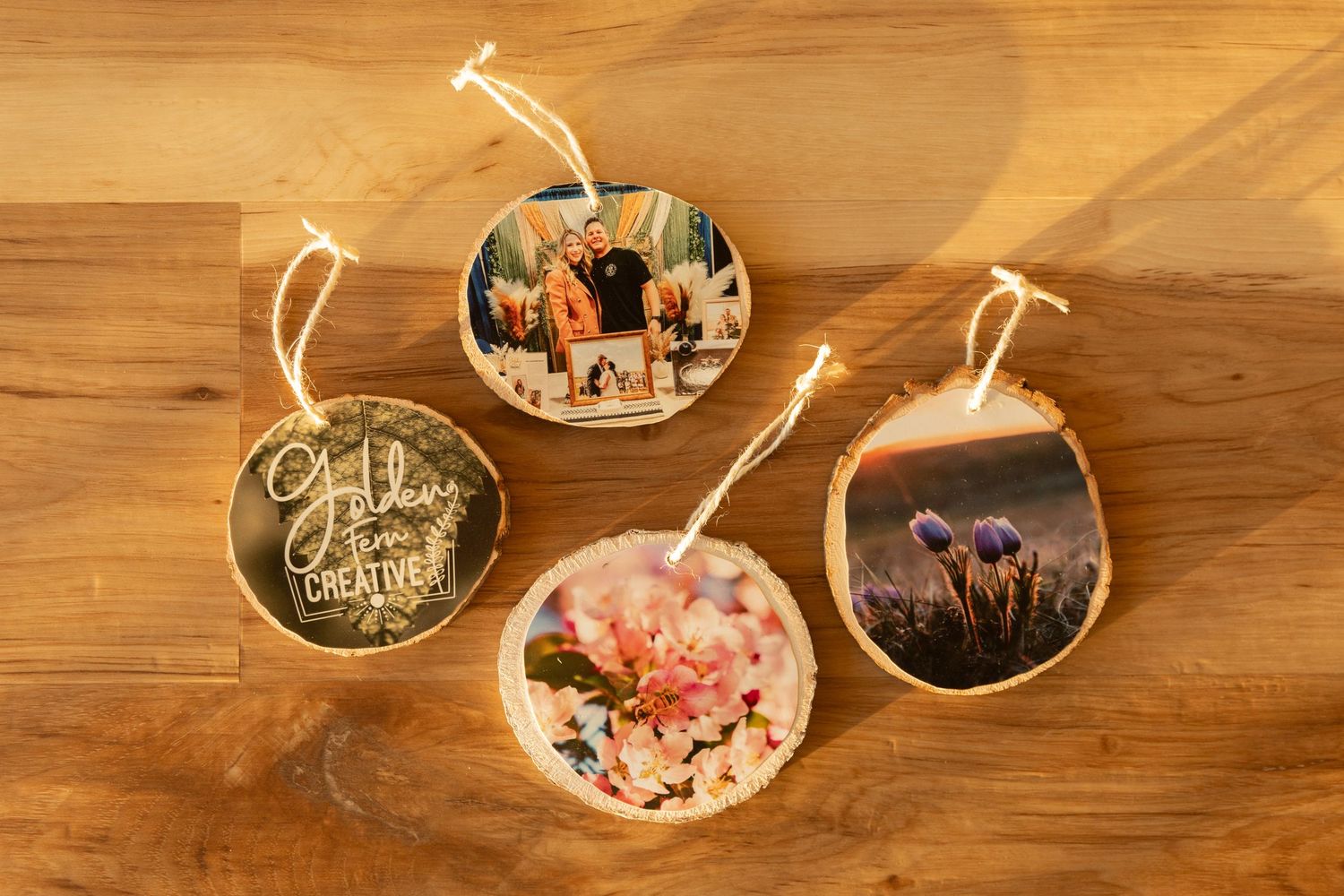 Four personalized photo ornaments made from wood slices with family photos displayed on a wooden surface.