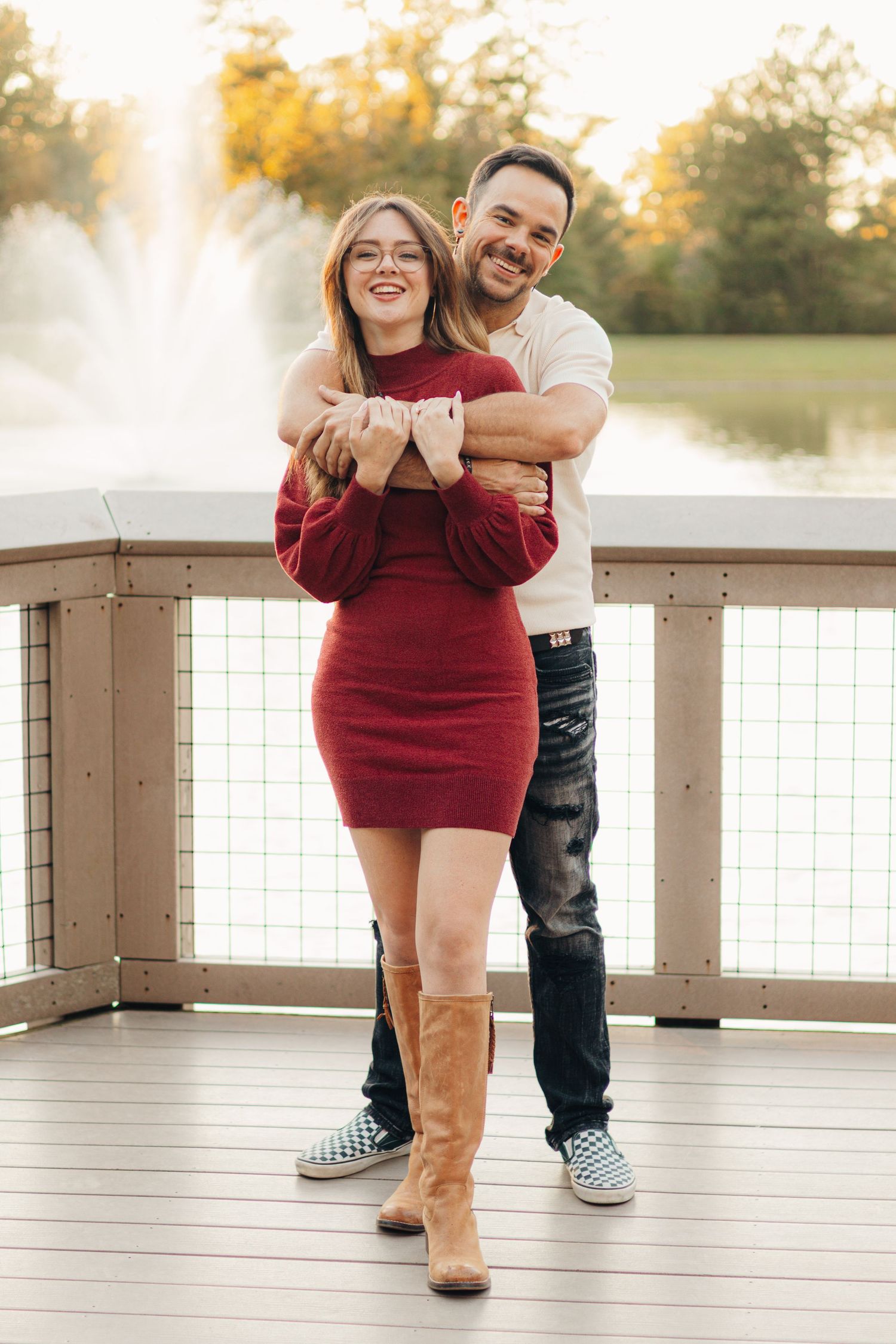Couple standing together on a wooden dock overlooking the water during a warm outdoor couples photography session.
