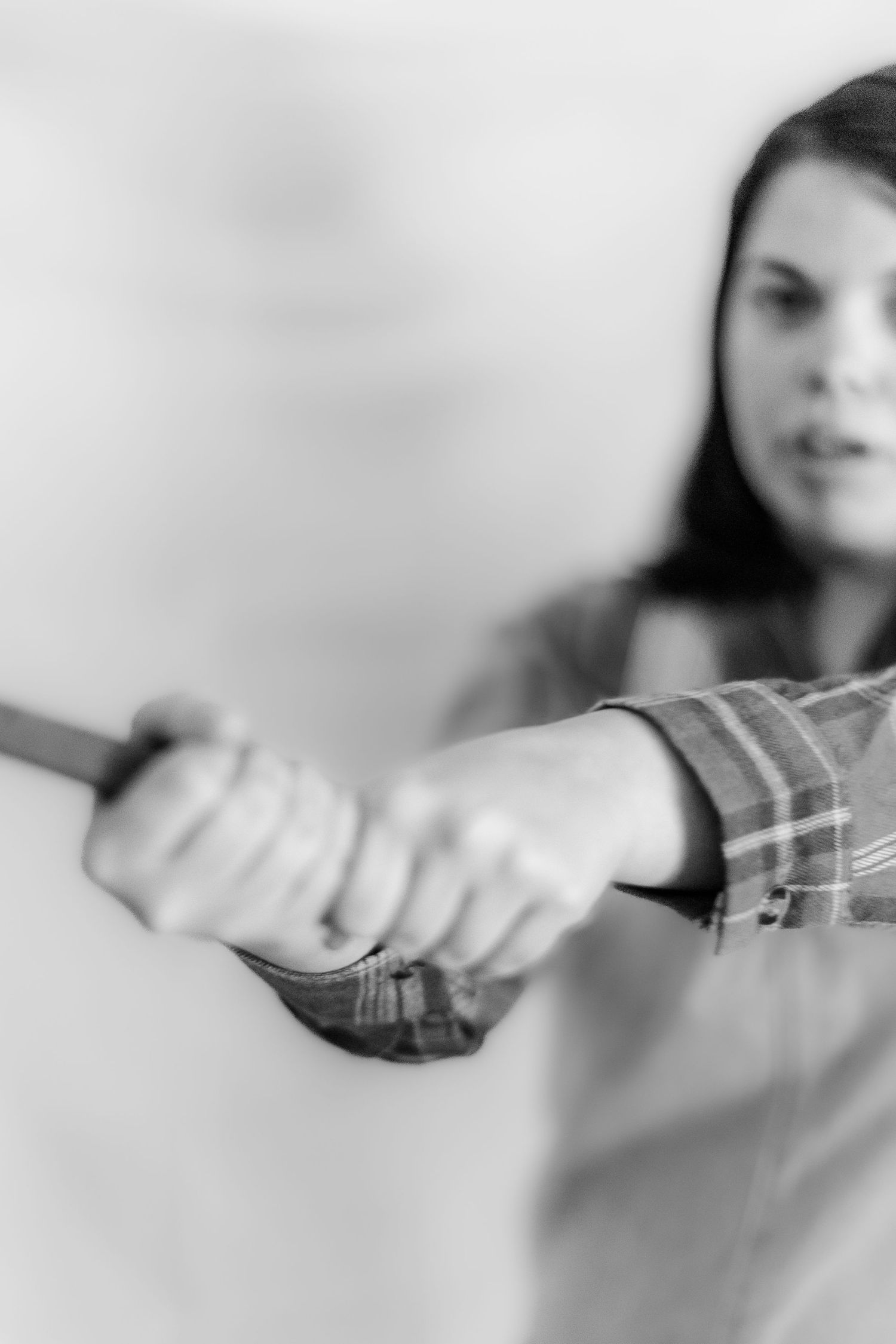 Black and white image of someone in a plaid shirt reaching forward with outstretched arms in a blurred motion.