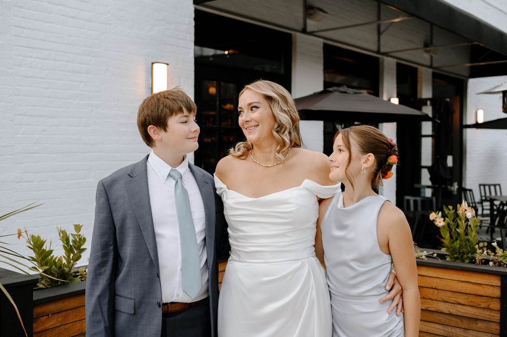 Wedding party stands together in a modern venue with white walls and wooden accents.