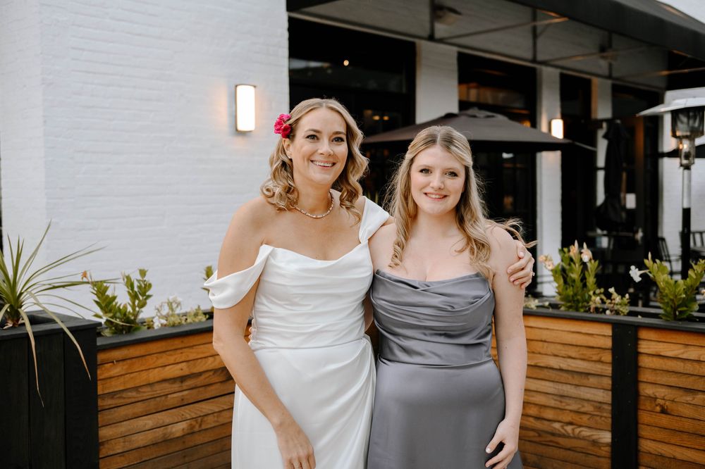Wedding guests gather for formal group photo outside modern restaurant with wood accents.