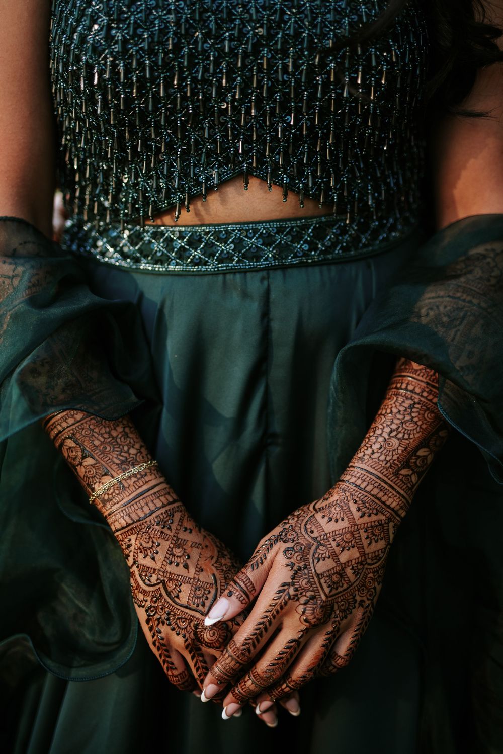 Detailed henna mehndi designs adorning hands with intricate patterns against a dark background.