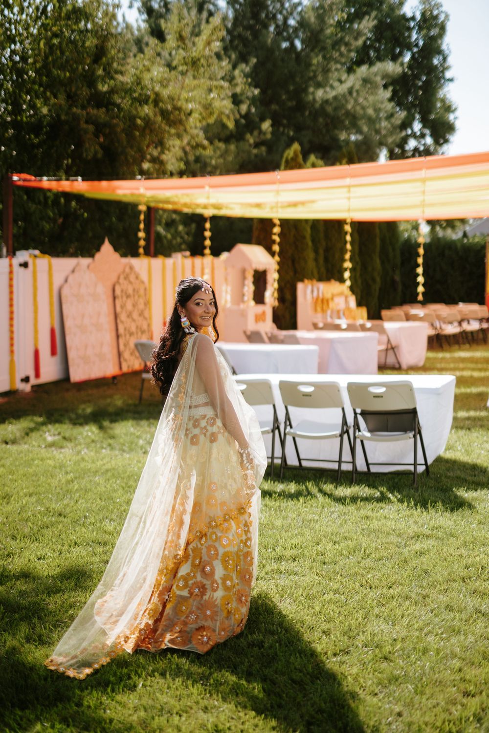 Colorful bohemian tents and lounge areas set up on green grass for an outdoor event with string lights overhead.