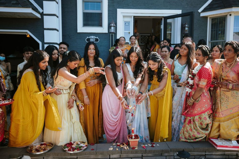 A group of people wearing colorful traditional Indian saris and outfits stand together in a line at a cultural celebration.