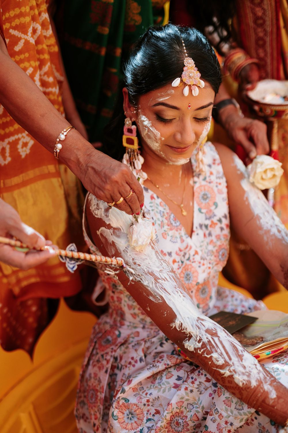 Traditional Indian wedding ritual showing hands being adorned with white rice powder during a ceremony.