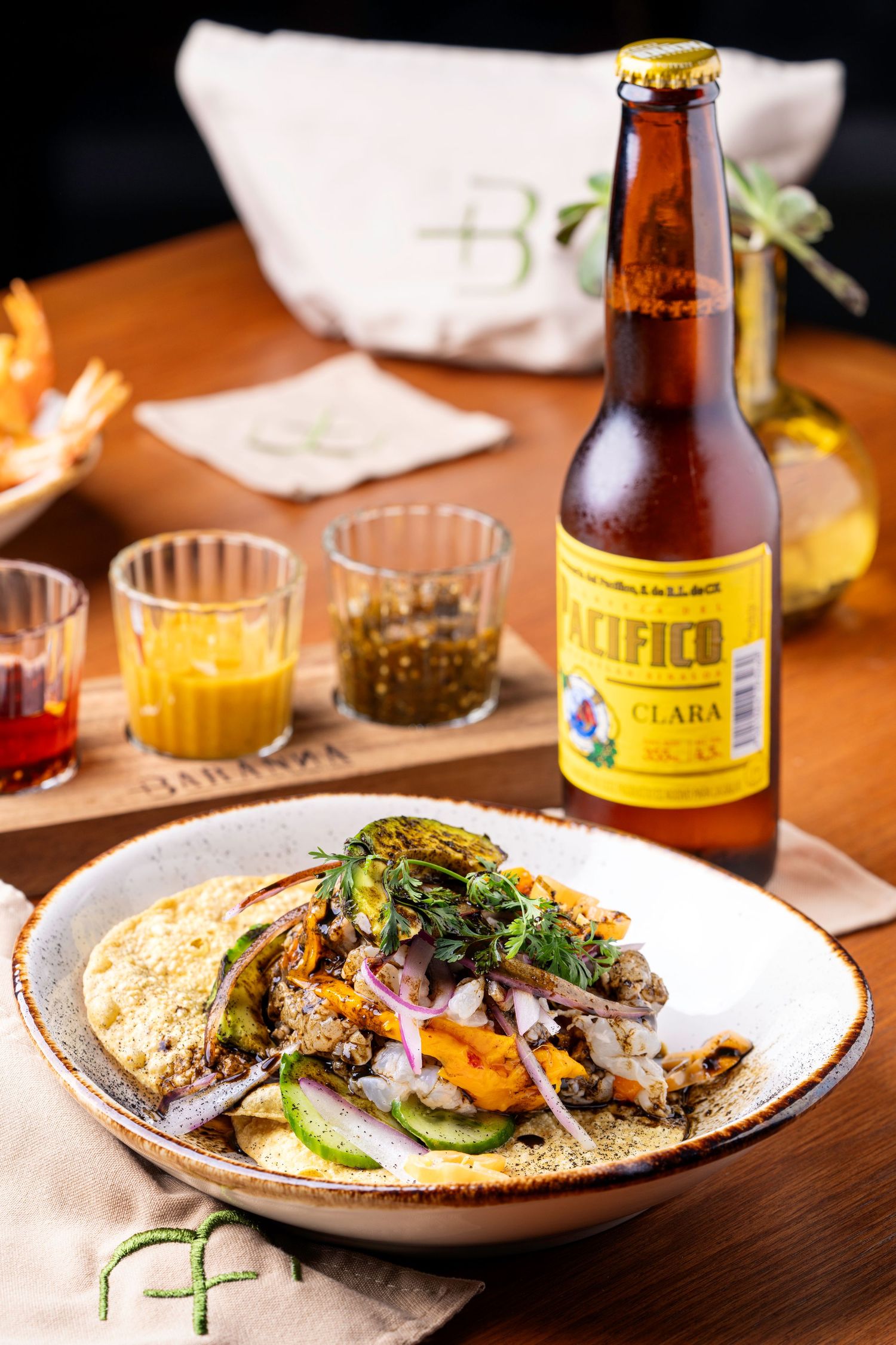 Delicious plated dishes with beer bottles on a wooden table in restaurant setting.