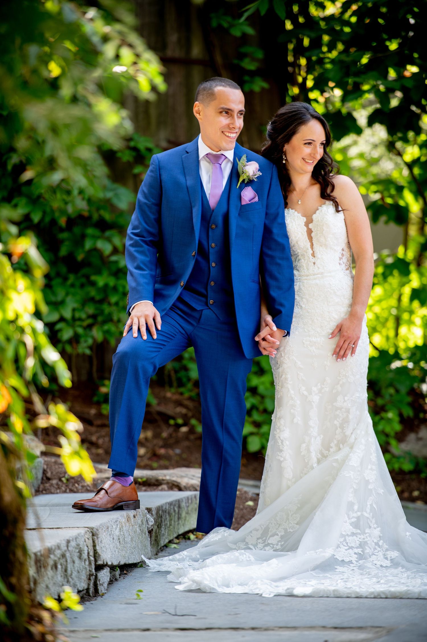 Elegant wedding photography on stone steps with flowing lace dress and navy suit.