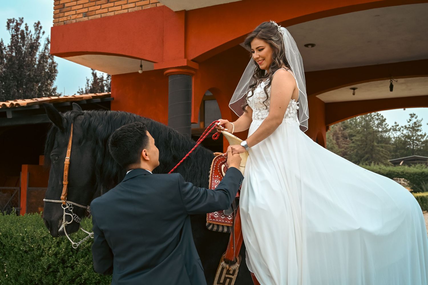 Wedding couple dancing outdoors with flowing white dress movement against orange building.