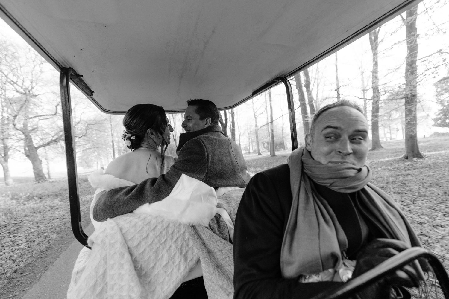 Black and white photo of couple seated in a golf cart with foggy autumn trees through the windows for Nova Scotia wedding photographer.