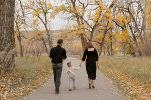 Three people walking away on autumn path surrounded by golden trees in Idian Battle Park.